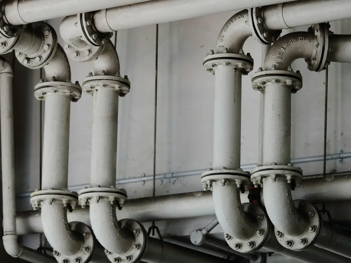 Flanged steel pipework running through a commercial plant room